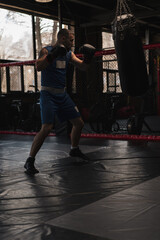 Obraz premium Boxing gym a boxer trains his punches hitting a punching bag