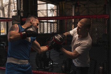 Fototapeta na wymiar Boxer Practices His Punches with His Coach in the Boxing Gym
