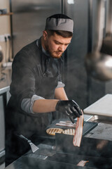 professional kitchen in hotel restaurant chef puts bacon for grill food concept