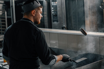 professional kitchen in a hotel restaurant the chef flips a burger patty with a spatula in the air