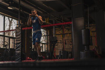 Fototapeta na wymiar A boxer in the gym who fights with the shadow practices punches