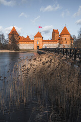 Naklejka na ściany i meble Medieval castle of Trakai, Vilnius, Lithuania, Eastern Europe, located between beautiful lakes and nature with wooden bridge in the early spring and frozen lake, vertical
