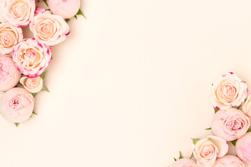 Obraz na płótnie Canvas Border frame made of pink rose flowers on a beige background. Place for your design.