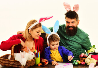 Mother, father and son preparing for Easter holiday. Easter family traditions. Easter Eggs. Happy parents and little child boy in bunny ears with painted eggs. Family celebrating Easter. Eggs hunt.
