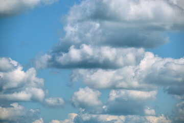 Bright landscape of white puffy cumulus clouds on blue clear sky.