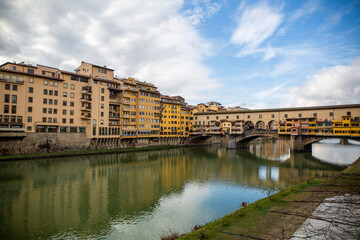 View of the Ponte Vecchio on the Arno river in the middle of the city of Florence with a sky with clouds, Italy