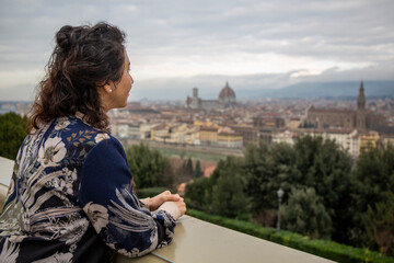 Fototapeta na wymiar Woman looks from above the city of Florence including the Cathedral Santa Maria del Fiore, which is the Duomo of Florence in the middle of the city in Italy