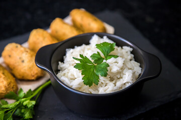 Bolinhos de bacalhau, very famous in Portuguese gastronomy. Fried dumpling, cod dumpling, fish, salted cod fritters, bacalao bunuelos. Codfish cake served with white rice on a dark background.