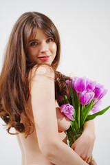 a gentle woman topless with tulips on a white background.