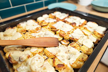 Homemade traditional potato casserole, sliced with plastics, baked with cheese in the oven until golden brown. Shallow depth of field, close-up.