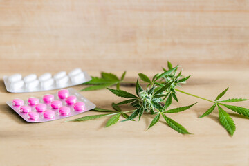 Marijuana buds flowers and prescription pills on table.