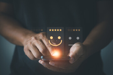 Businessman using smartphone to select smile face icon for client evaluation and customer satisfaction after use product and service . User give rating to service experience on online application.