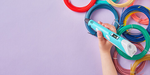 Banner with a kids hand holding 3d pen over the colorful heap of plastics. Hobby and modern toys...