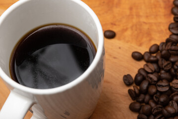 Black Coffee with Coffee Beans on the side on a Wood Board