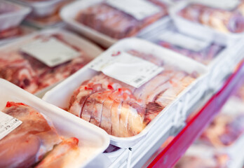 Sliced fresh raw chilled lamb meat in packages with labels on display in butcher shop..