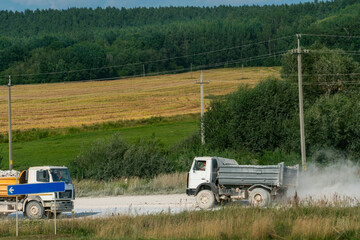 A dump truck is working on a sand quarry against the background of a forest. A truck is driving...