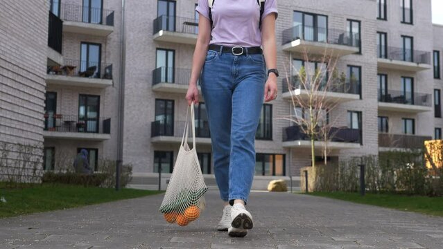 Woman supports ecology and vegetarianism, comes from the store with reusable cloth bags filled with vegetables.