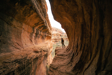 Young 30s woman steps out onto ledge in Subway Cave Boynton Canyon Az.