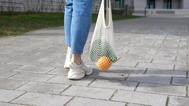 Woman supports ecology and vegetarianism, comes from the store with reusable cloth bags filled with vegetables.