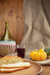 wicker wine bottle, pumpkins and glass of wine on wooden background