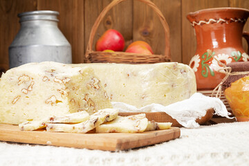 homemade cheese with nuts and pitcher of milk on wooden table.