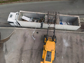 Skid steer loader loading a truck with waste material transferred for further sorting, treatment,...