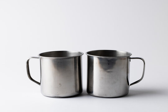 Close up of two metal cups on white background with copy space