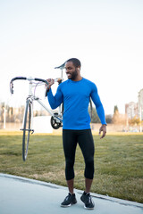 A dark-skinned person is happily doing outdoor sports, the black man is keeping the bike by hand. Concept of sport in African Americans.