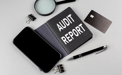AUDIT REPORT text written on black notebook with smartphone, magnifier and credit card