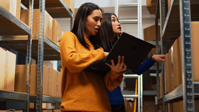 Team of women doing stock logistics with computer, checking merchandise for distribution management. Business partners looking at logistics data on laptop, financial planning.