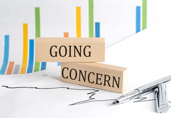 GOING CONCERN text on notebook with pen and pencil on grey background