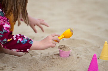 A child plays with sand on the beach