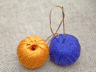 a needle with a blue and yellow thread stuck in a skein