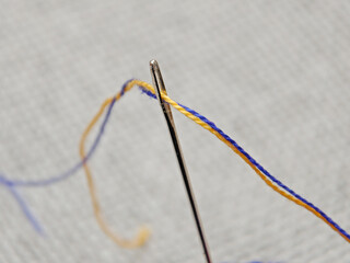 needle with blue and yellow threads, close-up