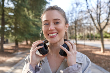 Young caucasian woman finds solace and inspiration in her favorite tunes while walking in the park.