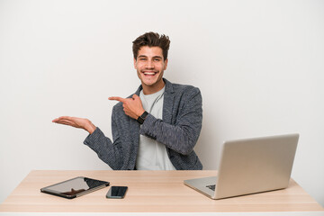 Young entrepreneur man working with a laptop isolated excited holding a copy space on palm.