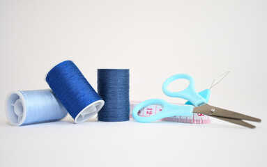 Sewing kit consisting of three spools of blue thread in different shades, scissors and measuring...