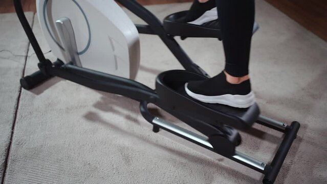 close up female legs running on elliptical orbitrek machine in fitness gym