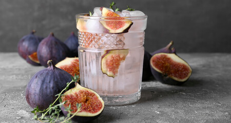 Glass of tasty fig lemonade on grey table