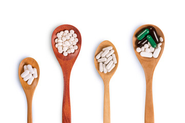 Medicine pills in wooden spoon on white background. Top view