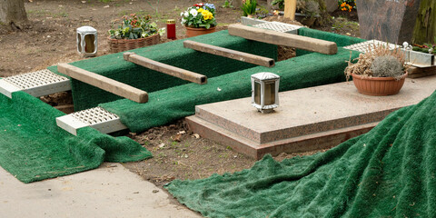 an dug grave with green grass mats just before a burial in a cemetery - obrazy, fototapety, plakaty