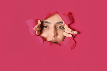 Young woman visible through hole in pink paper