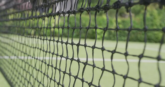 Close up of tennis net and ball on tennis court in garden on sunny day