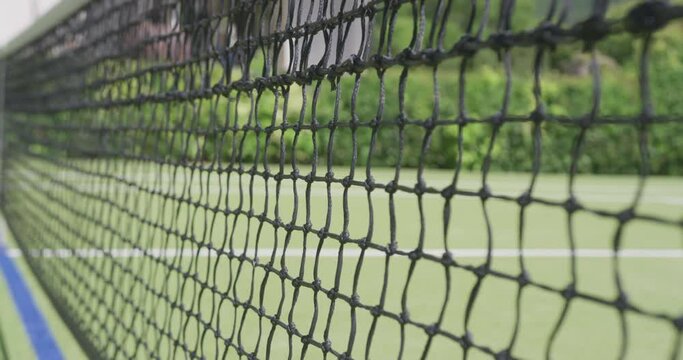 Close up of tennis net and ball on tennis court in garden on sunny day