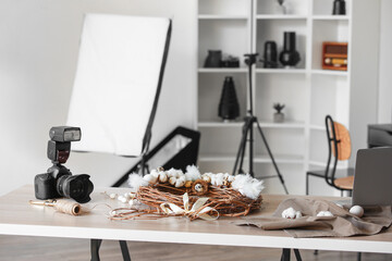 Professional camera and Easter wreath on table in photo studio