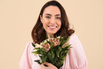 Young woman in pink dress with alstroemeria flowers on beige background, closeup