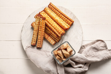 Board of wafer rolls with boiled condensed milk on white wooden background