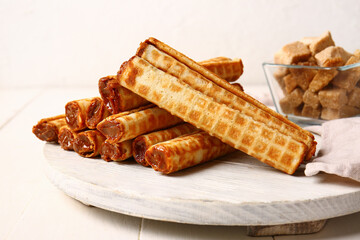 Board of wafer rolls with boiled condensed milk on white wooden table