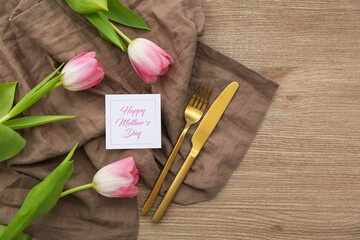Table setting for Mother's Day celebration with tulip flowers on wooden background