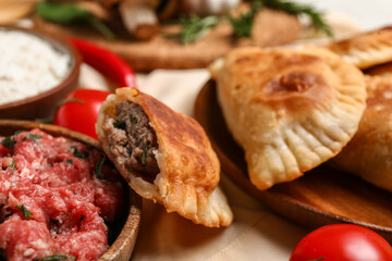 Tasty meat empanadas and ingredients on table, closeup